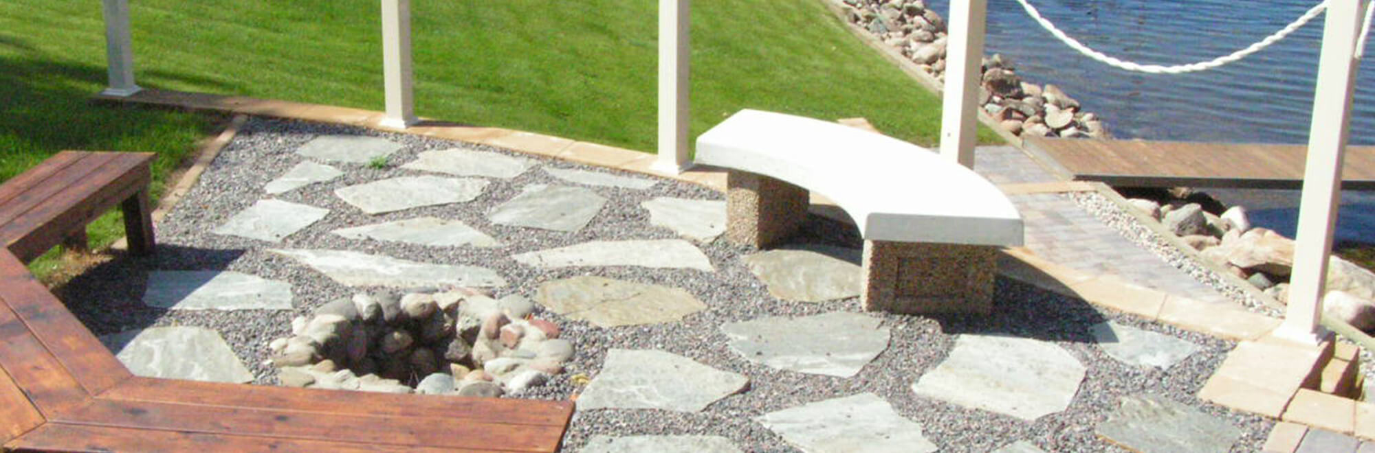 Stone patio areat with curved seating benches around an in-ground fire pit